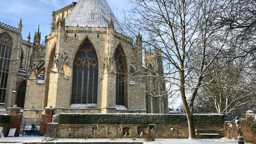 Snowy garden looking towards part of a grand Minster building